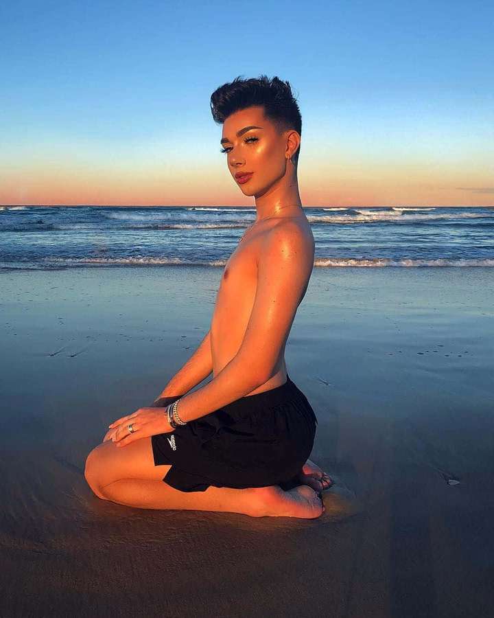 Person sitzt im Schneidersitz am Strand bei Sonnenuntergang mit Meereswellen im Hintergrund. — James Charles Bilder