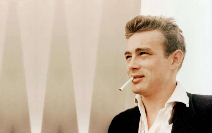 James Dean in a black jacket and white shirt holding a cigarette. — James Dean Wallpaper