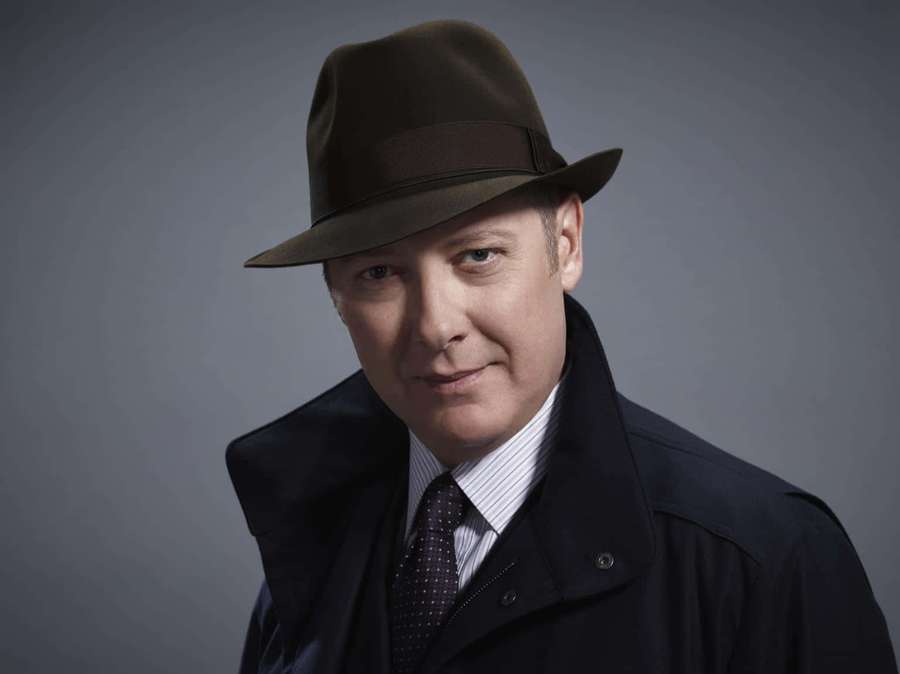 Mann iført brun fedora og mørk frakk med et subtilt smil mot en grå bakgrunn. — James spader Bakgrunner