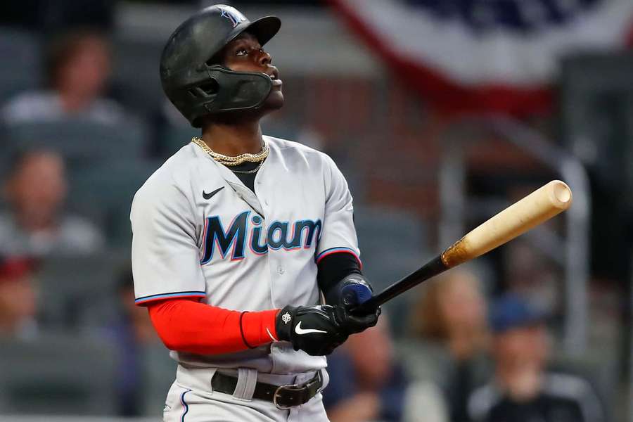 Baseballspieler in Miami-Uniform hält Schläger und blickt während Nachtspiel nach oben. — Jazz Chisholm Wallpaper