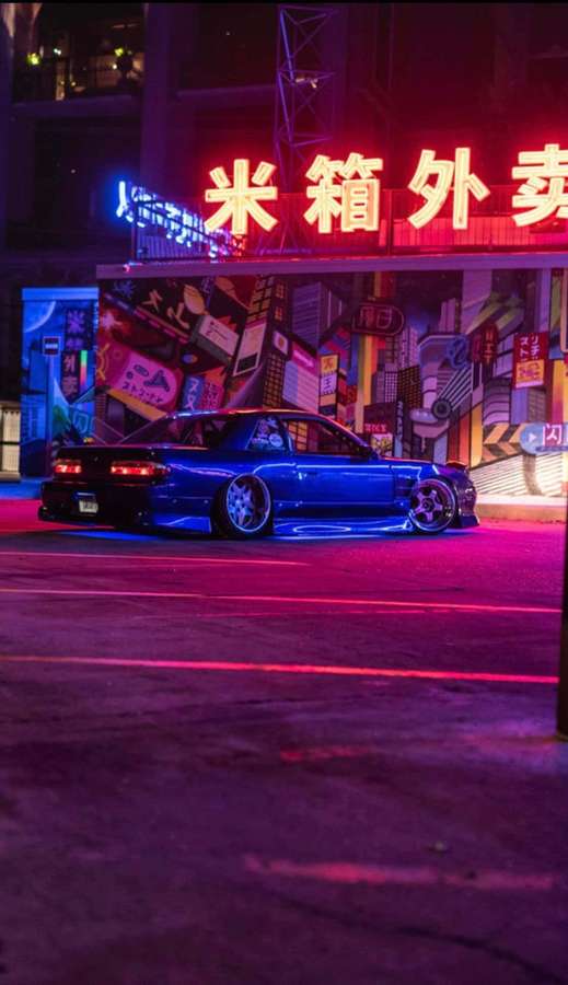 Blue sports car parked under glowing neon signs in a bustling city at night. — Jdm Picture