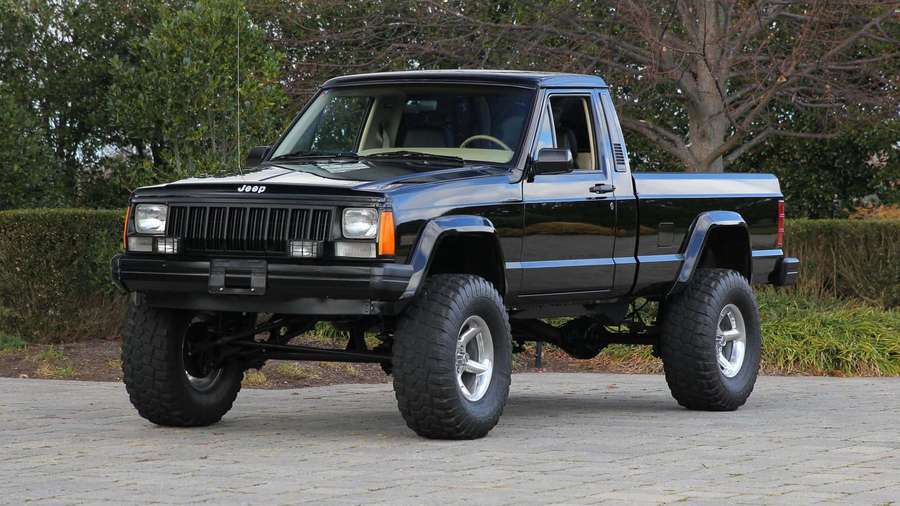 Camioneta Jeep Cherokee negra levantada estacionada en camino pavimentado con árboles y arbustos detrás. — Jeep Comanche Fondos de pantalla