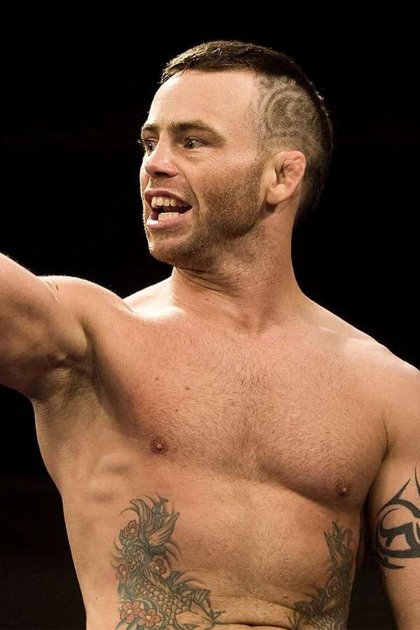 A tattooed man with a shaved head shouts with intensity. — Jens Pulver Wallpaper