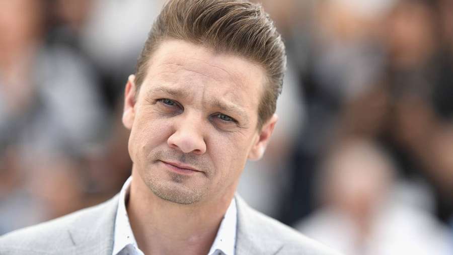 Schauspieler Jeremy Renner in einem grauen Anzug, der bei einer Veranstaltung im Freien ernst dreinschaut. — Jeremy renner Wallpaper