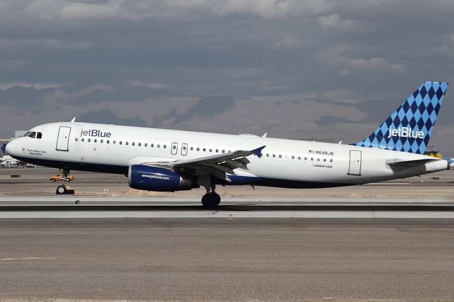 JetBlue Flugzeug auf Landebahn mit Bergkulisse unter bewölktem Himmel — Jetblau Wallpaper