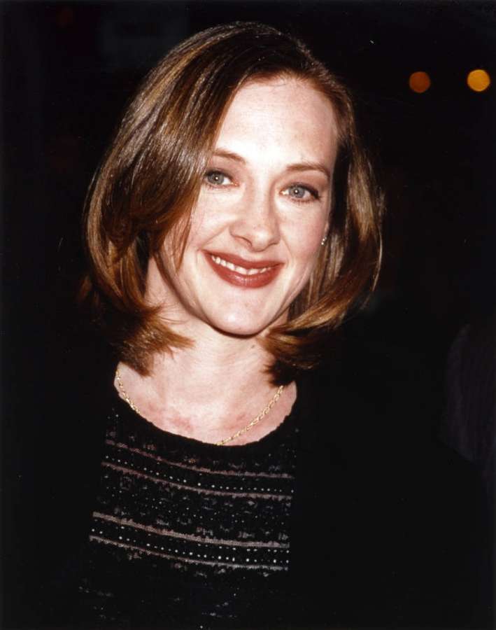 Eine lächelnde Frau mit braunen Haaren, die ein schwarzes Oberteil und eine goldene Halskette bei einer Abendveranstaltung trägt. — Joan Cusack Bilder