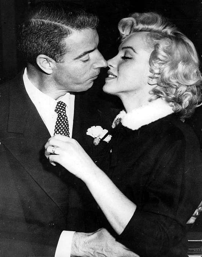 Marilyn Monroe and a man sharing an intimate kiss in a black and white photo. — Joe Dimaggio Background