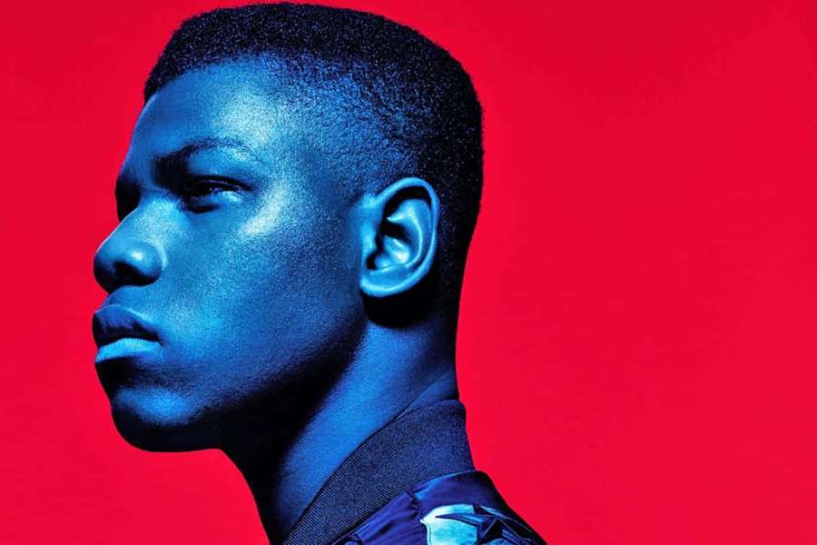 Young man in profile under blue light against red background — John Boyega Wallpaper