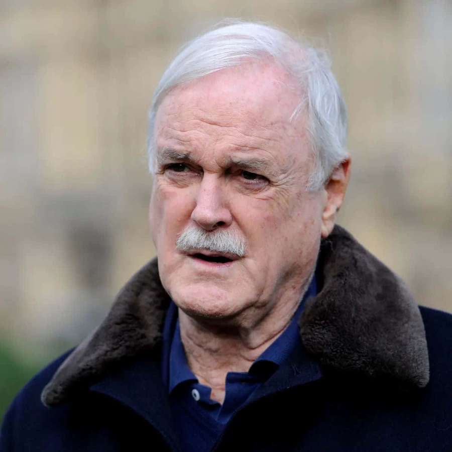 Anciano con cabello blanco y bigote usando abrigo oscuro con cuello de piel. — John cleese Fondos de pantalla