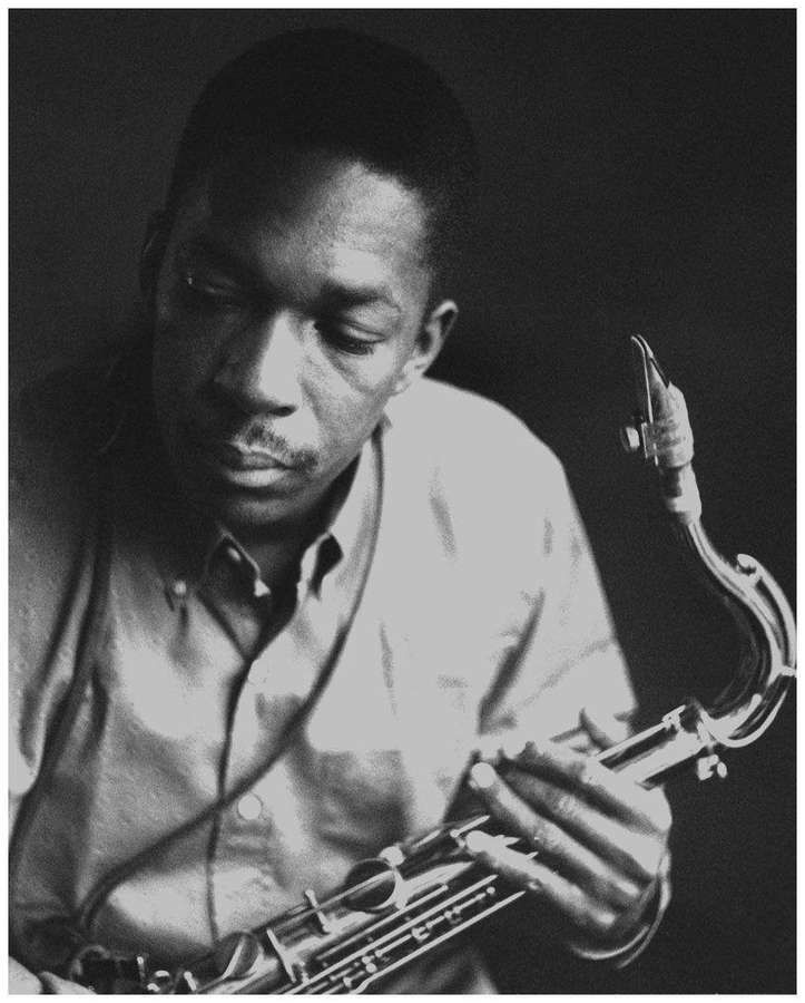 A jazz saxophonist playing his instrument in a black and white studio portrait. — John Coltrane Wallpaper