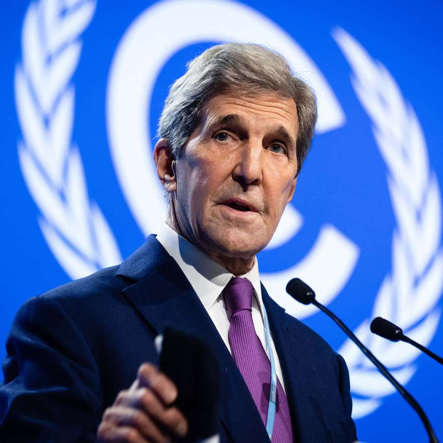 Man in suit speaking at UN podium with microphone — John Kerry Wallpaper