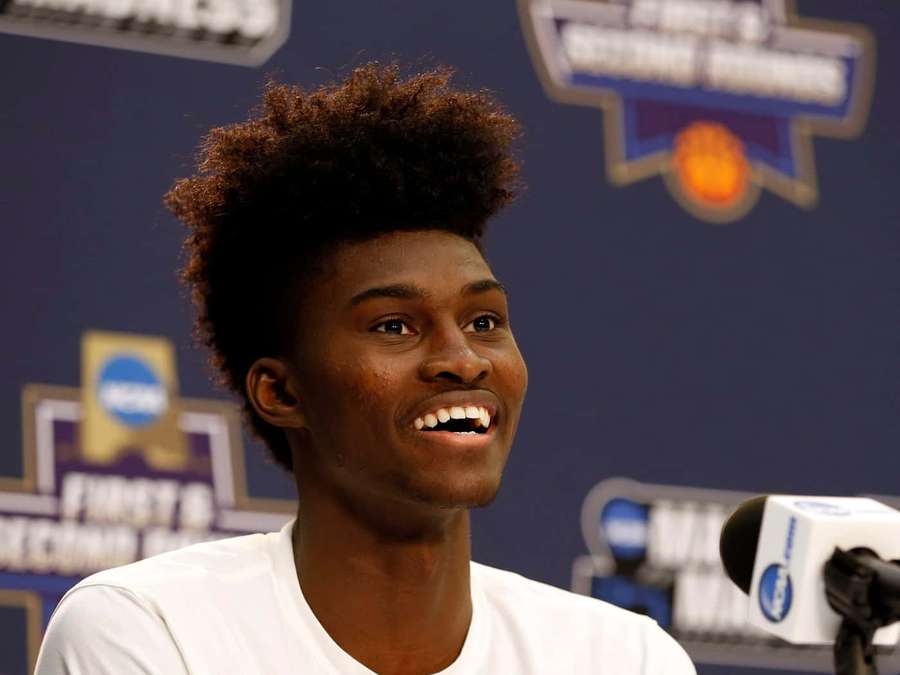 Young basketball player smiling at press conference with NCAA logos behind him. — Jonathan Isaac Wallpaper