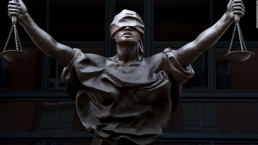 Bronze statue of blindfolded Lady Justice holding scales outdoors. — Judicious Wallpaper