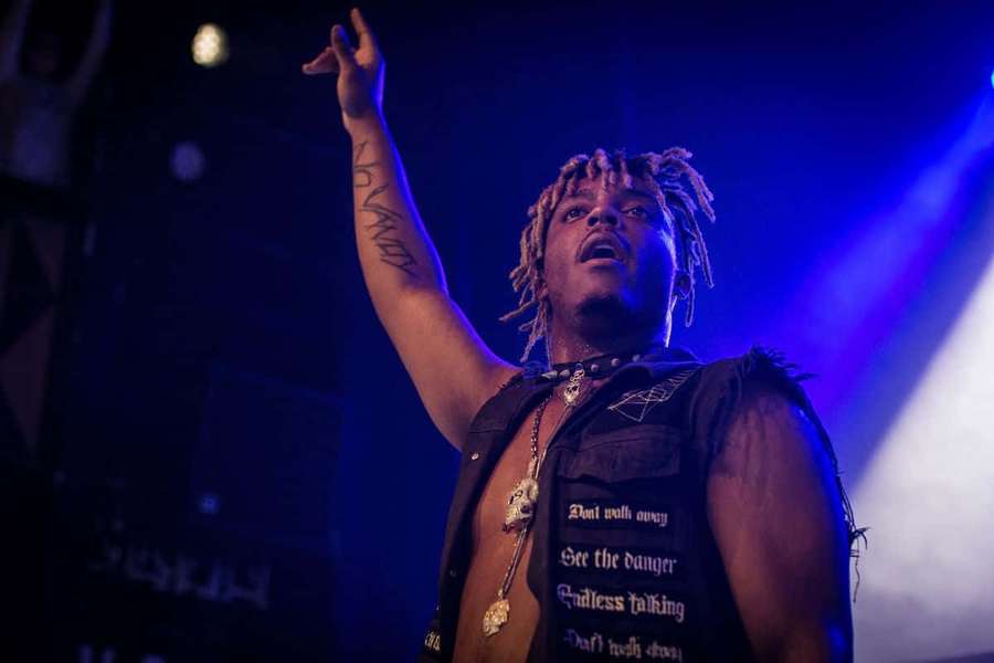 Male rapper performing on stage with raised hand under blue lights. — Juice Wrld Live Wallpaper