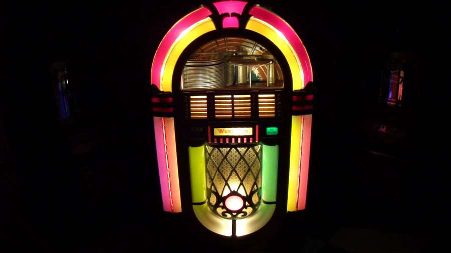 A glowing vintage jukebox with neon lights in a dark room. — Jukebox Wallpaper