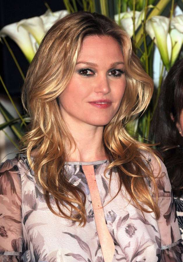 Frau mit blonden Haaren und Blumenbluse lächelt in die Kamera, weiße Lilien hinter ihr. — Julia Stiles Bilder