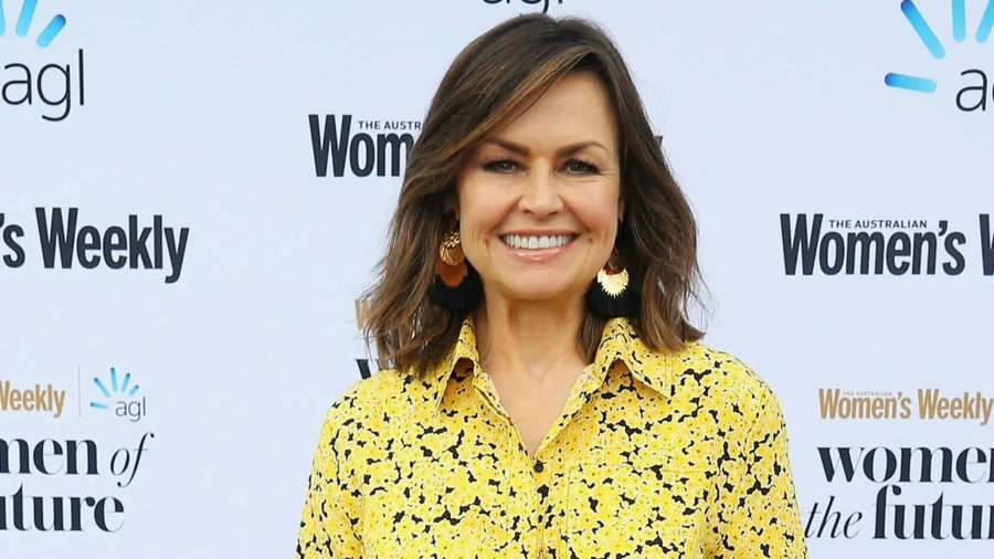 Woman in yellow patterned shirt smiling at event with branded backdrop. — Julie Walters Wallpaper