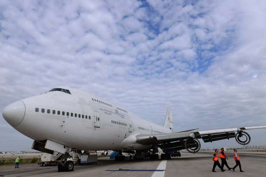 Großes weißes Flugzeug auf Vorfeld mit Bodenpersonal in orangefarbenen Westen in der Nähe unter bewölktem Himmel — Jumbo Jets Wallpaper