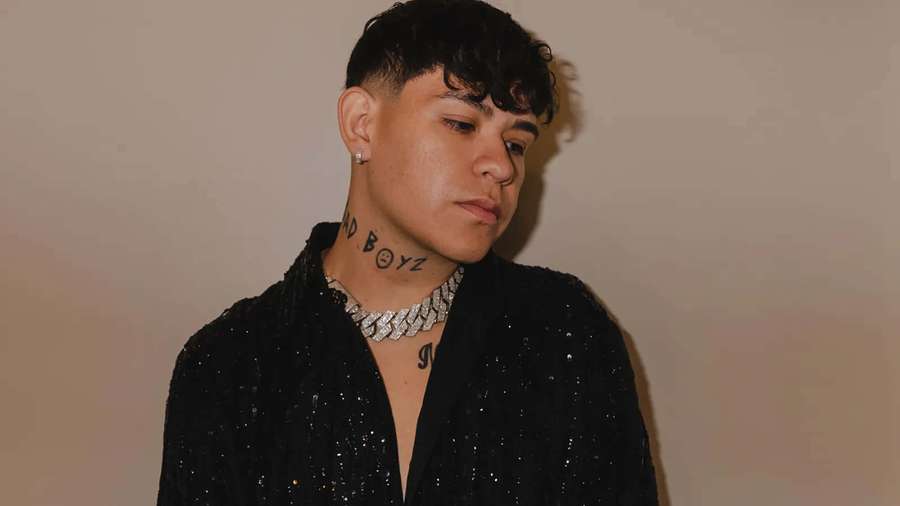 Young man with tattoos wearing sparkly black jacket and diamond chain. — Junior H Wallpaper