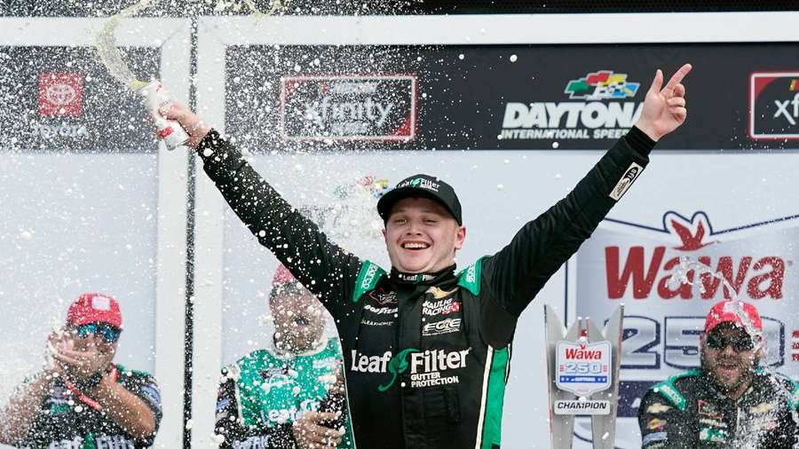Race car driver spraying champagne on podium after winning championship. — Justin Haley Wallpaper