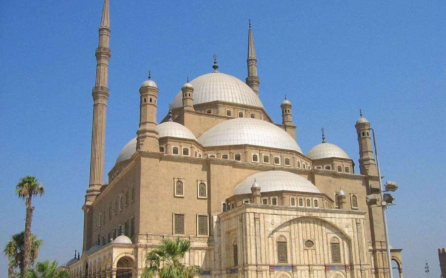Suuri kivimoskeija, jossa on kupoleja ja minareetteja kirkkaan sinisen taivaan alla palmujen kanssa. — Kairo Taustakuvat