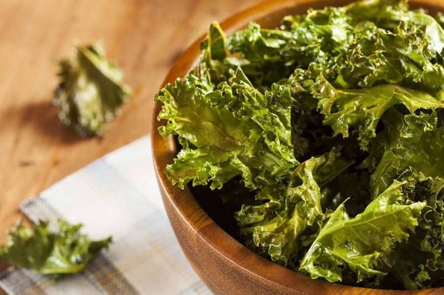 Crispy kale chips in a wooden bowl on a checkered cloth. — Kale Wallpaper