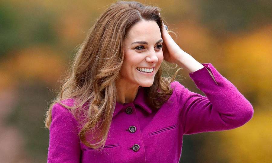 Woman in magenta coat smiling with hand in hair outdoors in autumn. — Kate Middleton Background