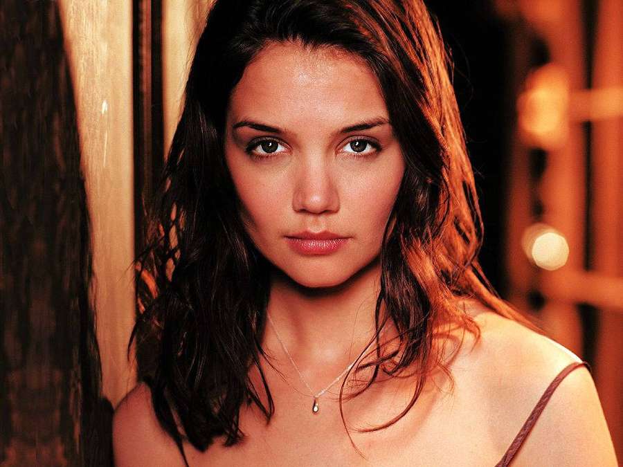 A woman with dark hair looks directly at the camera in warm golden light. — Katie Holmes Wallpaper