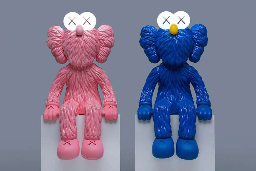 Two stylized KAWS sculptures one pink one blue sitting on pedestals — Kaws Background
