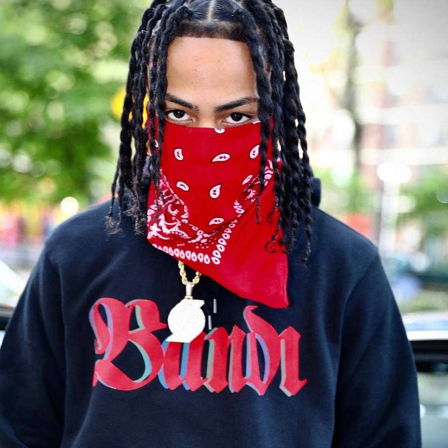 Person mit Zöpfen, die ein rotes Bandana und einen schwarzen Hoodie mit roter Schrift trägt. — Kay Flock Hintergrundbild