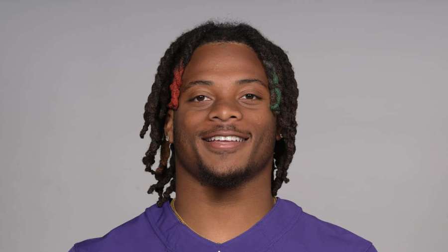 A smiling man with colorful dreadlocks wearing a purple shirt. — Keaton Mitchell Wallpaper