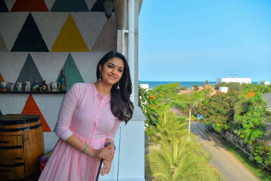 Donna in vestito rosa che sorride sul balcone con vista sull'oceano — Keerthi Suresh Sfondi