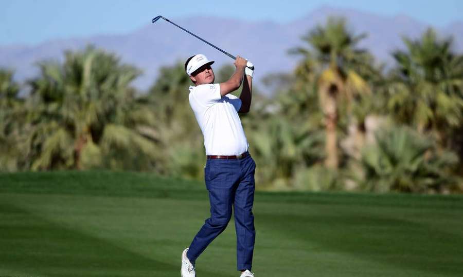 Golfer swinging club on sunny golf course with palm trees and mountains. — Keith Mitchell Picture