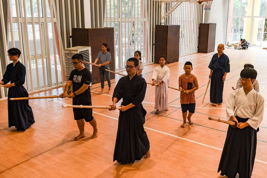 Schüler trainieren Kampfsport mit Holzschwertern in einer Turnhalle. — Kendo Bilder