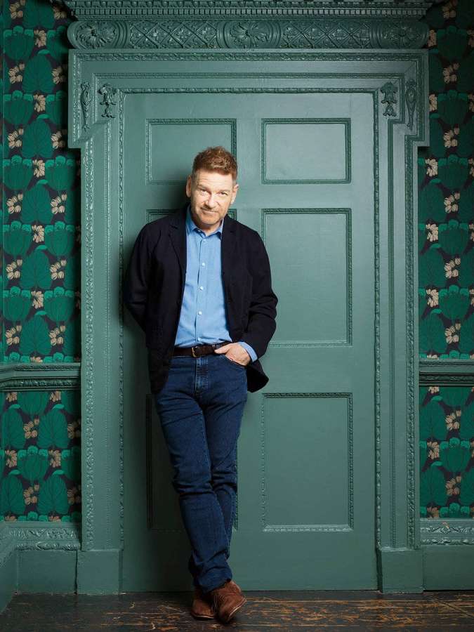 Mann lehnt an einer grünen Tür in einem Raum mit gemusterter Tapete. — Kenneth Branagh Bilder