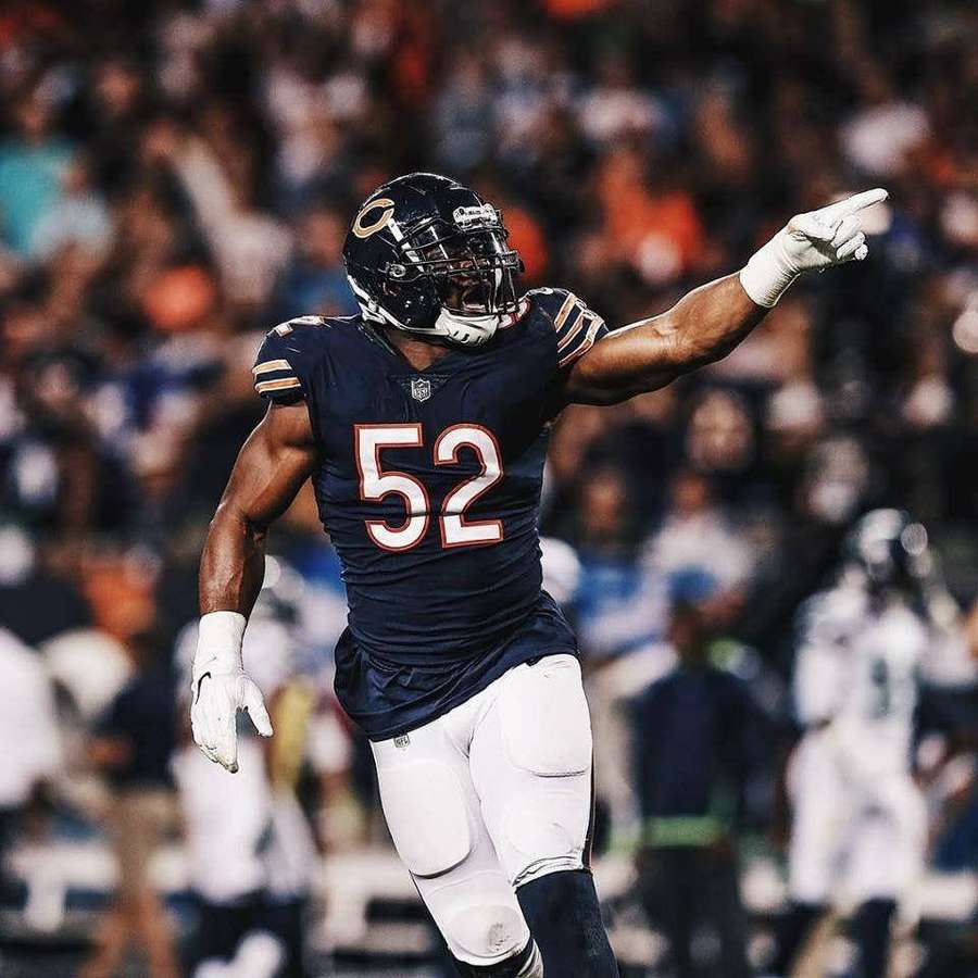 Football player number 52 celebrating with arm raised at night game. — Khalil Mack Background