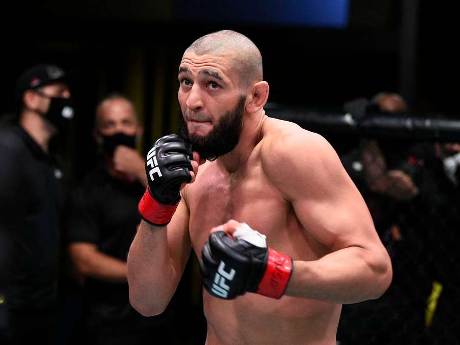 A focused MMA fighter in red and black gloves inside an octagon. — Khamzat Chimaev Background