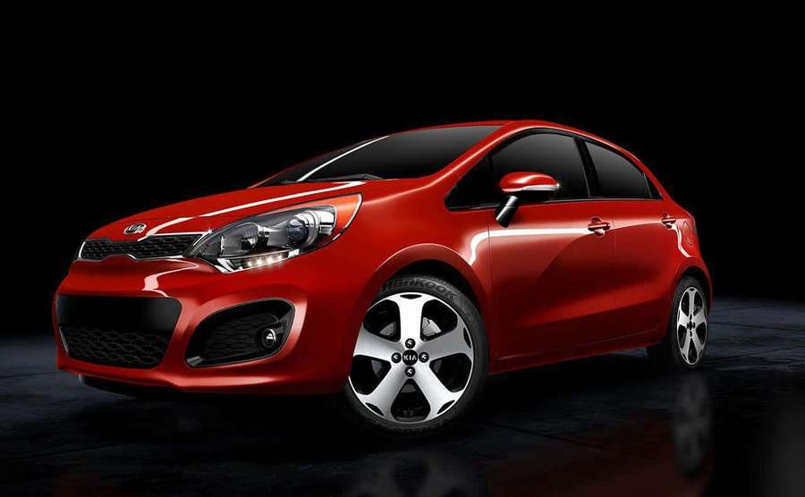A red Kia car with silver rims on a dark reflective studio floor. — Kia Rio Wallpaper