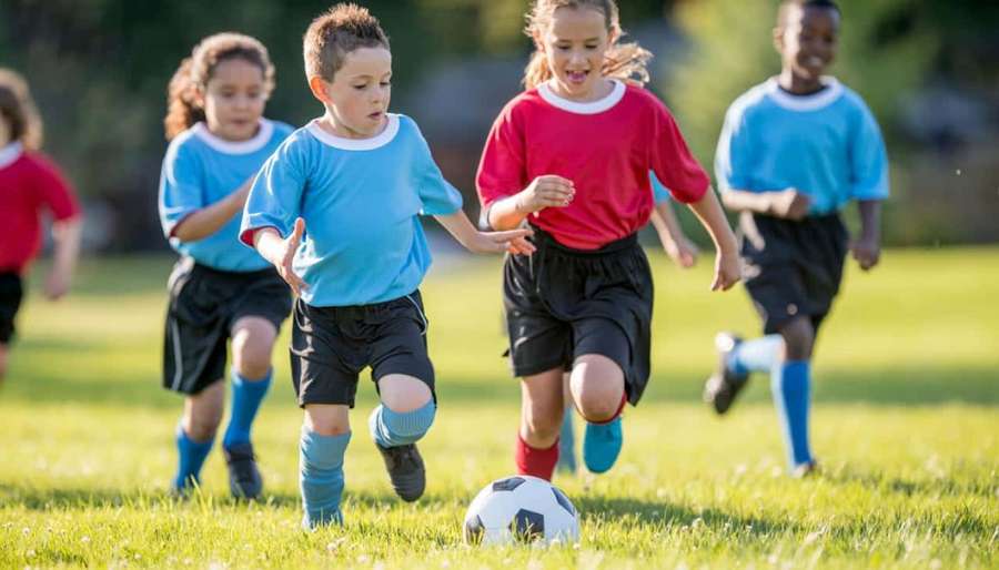Children playing soccer on a sunny grass field. — Kids Soccer Wallpaper