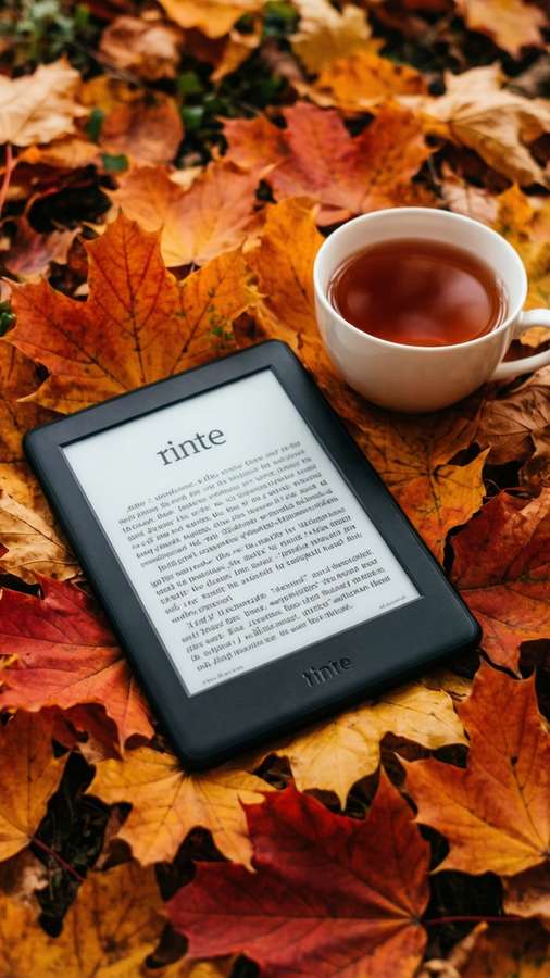 A Kindle with tea and autumn leaves, perfect for fall-themed wallpapers. — Kindle Wallpaper