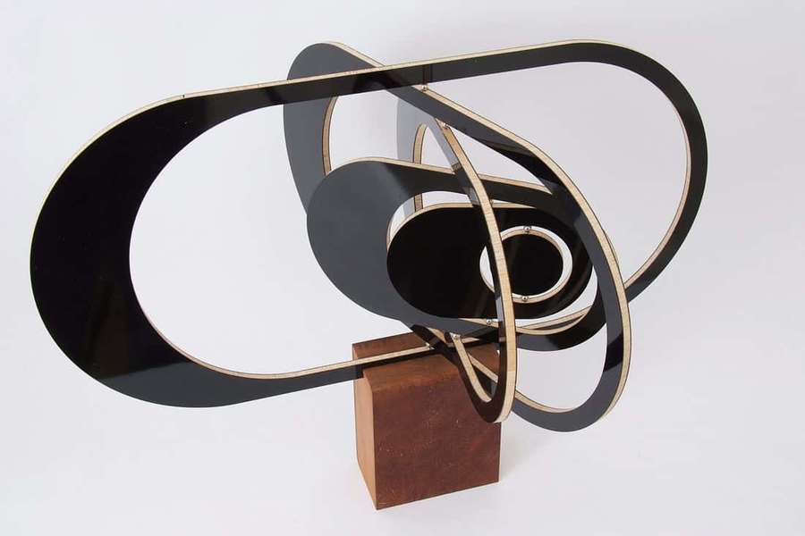 Abstract sculpture with black and gold loops on wooden base. — Kinetic Art Wallpaper