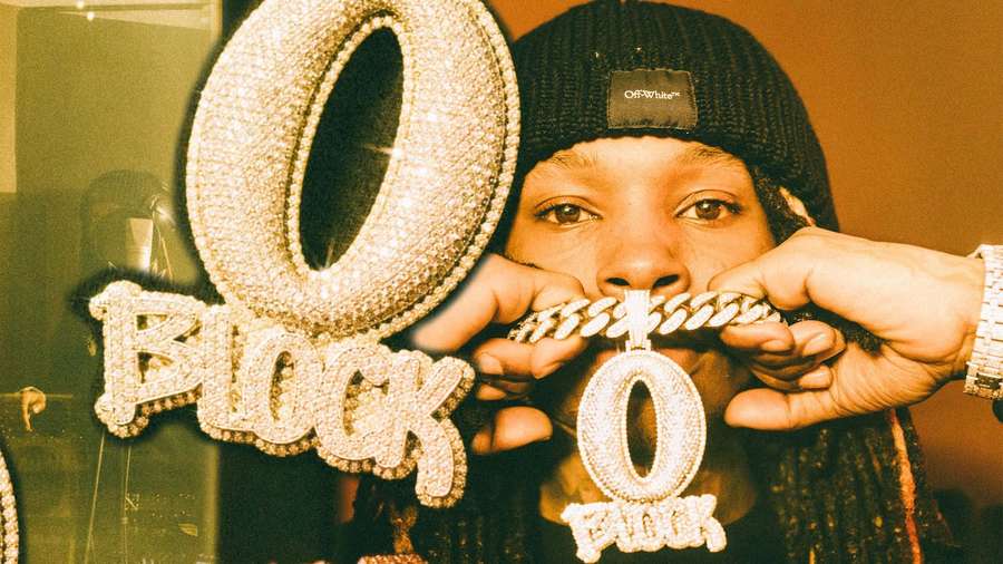 Person wearing a beanie holding a diamond-encrusted 'O BLOCK' sign and chain. — King Von Background