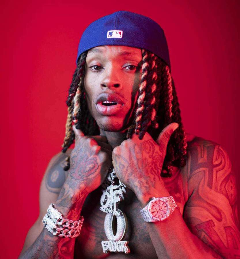 A tattooed man in a blue cap and gold chains poses against a red background. — King Von Drip Wallpaper