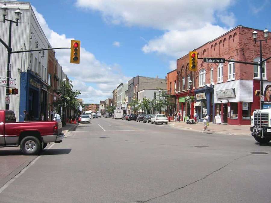 Urban street scene with brick buildings and cars under a blue sky. — Kitchener Picture