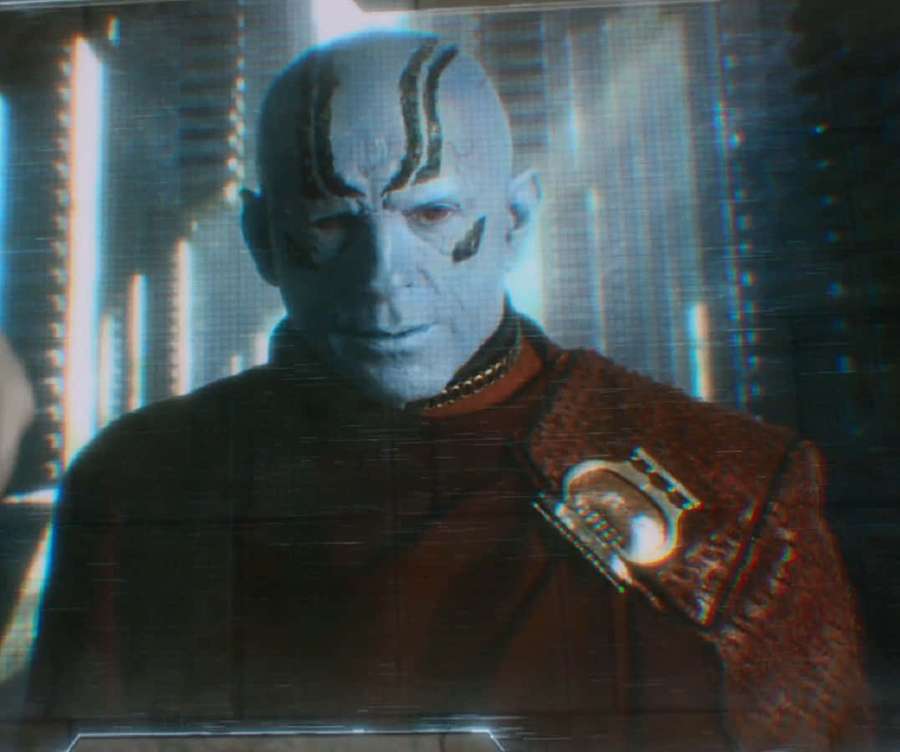 Een serieuze alien in rood uniform met gloeiende tech-achtergrond. — Kree Achtergronden