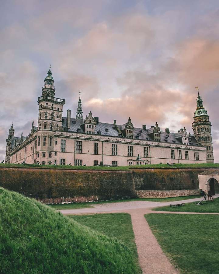 A majestic castle with turrets and stone walls surrounded by green grass and a winding path. — Kronborg Castle Wallpaper