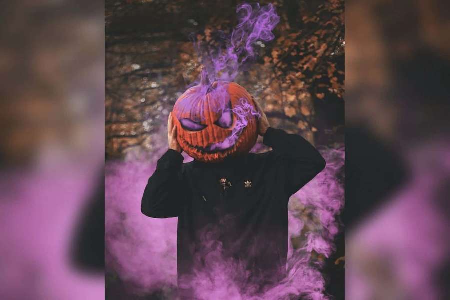 Person hält einen rauchenden Jack-o-Lantern in einem gruseligen Wald mit lila Rauch. — Kürbiskopf bilder