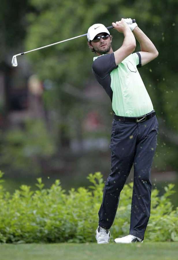 Golfista en medio del swing en un campo de golf soleado con césped verde y árboles al fondo. — Kyle Stanley Fondos de pantalla