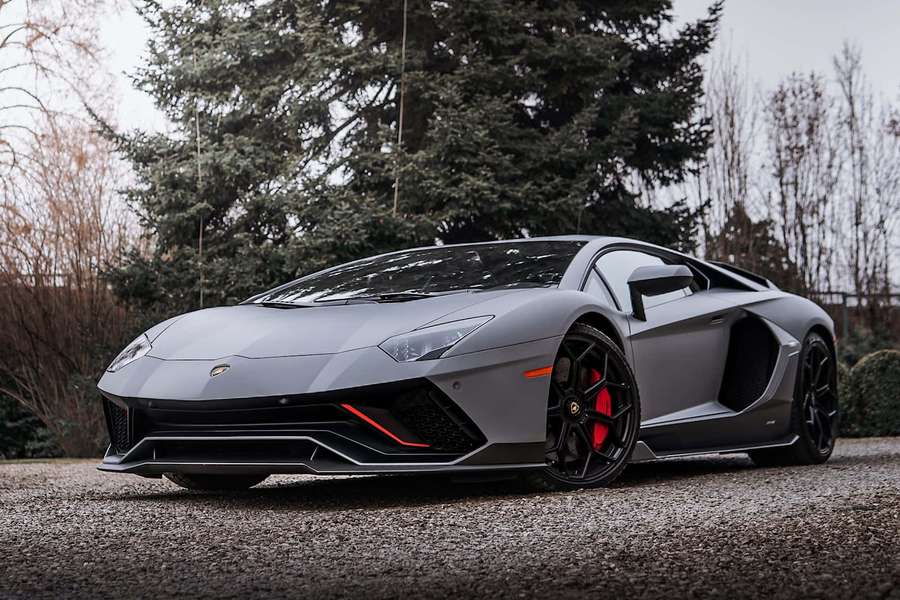 Matte gray Lamborghini Aventador with red brakes parked on gravel near trees. — Lamborghini Picture