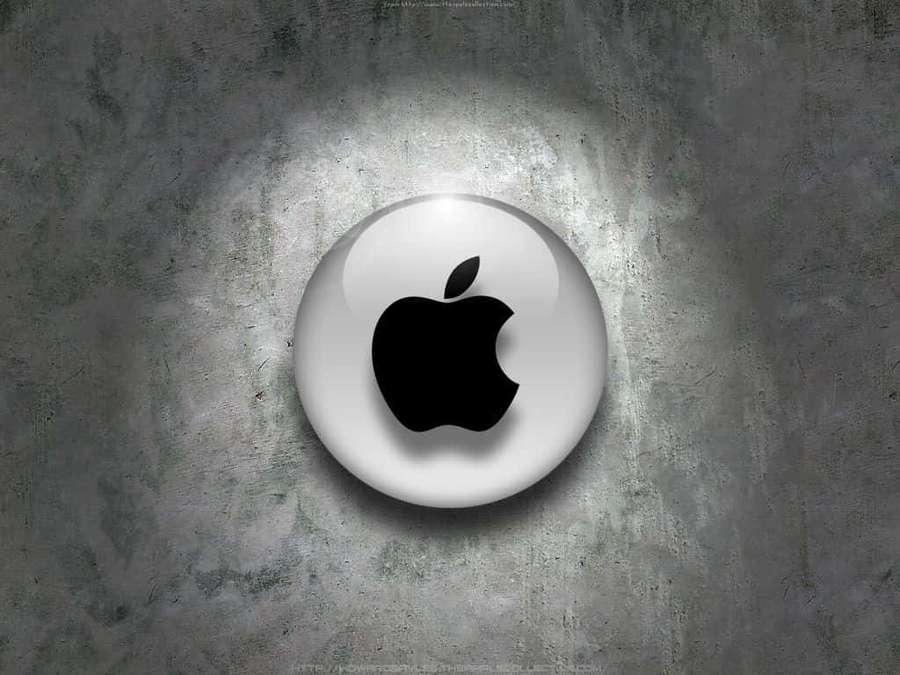 Glossy Apple logo on textured gray concrete wall under spotlight. — Laptop Apple Wallpaper